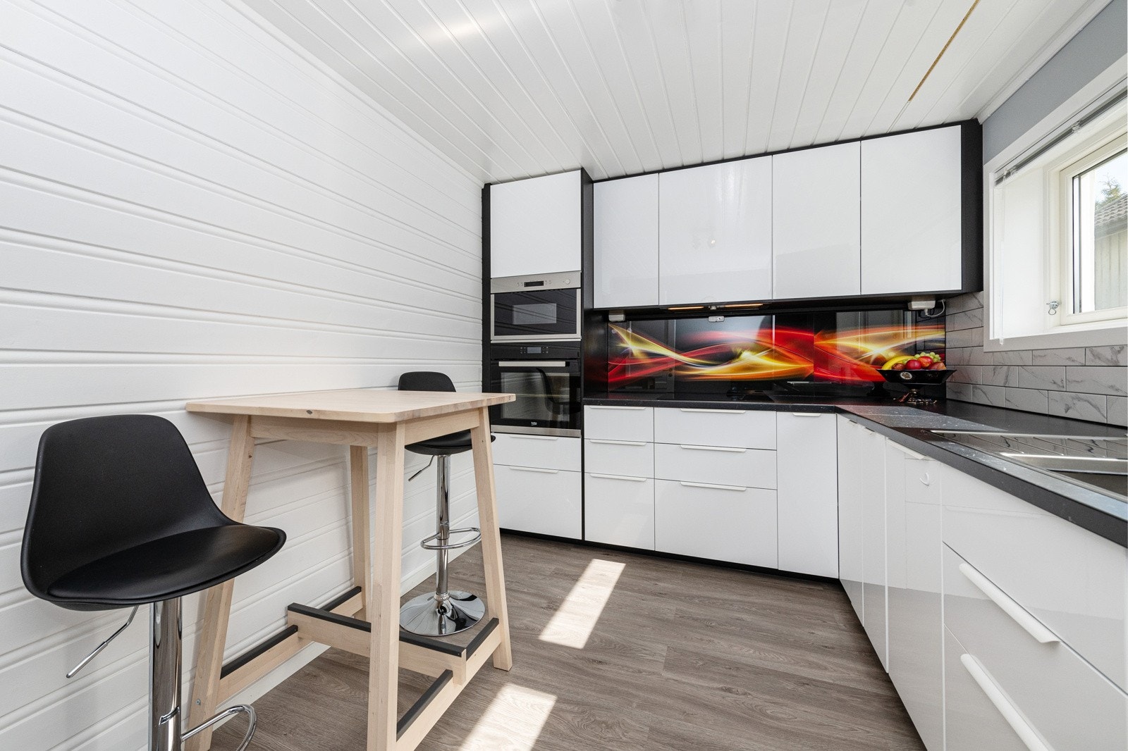 I underetasjen er det kjøkken med moderne kjøkkeninnredning med høyglans fronter og benkeplate av laminat. Her er det god benk- og skapplass. Galleribilde