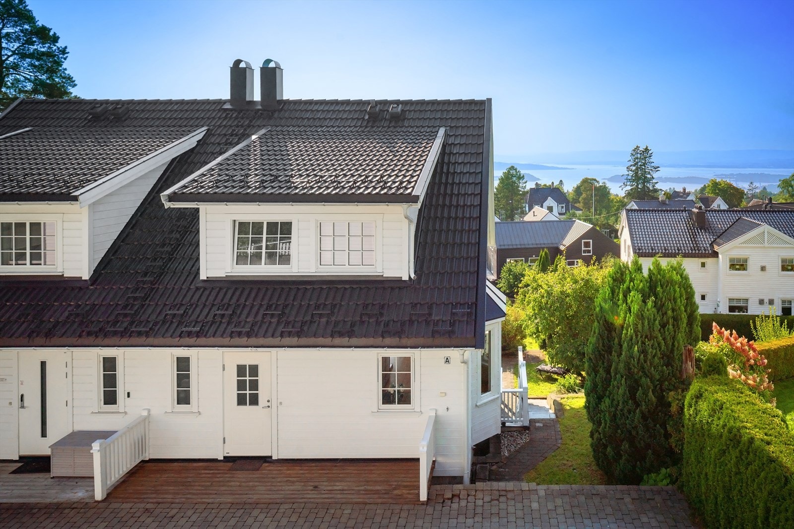Pen fasade med mulighet for kafesett ved inngangspartiet. Trapp/platå til høyre ned til hage og terrasse. Galleribilde