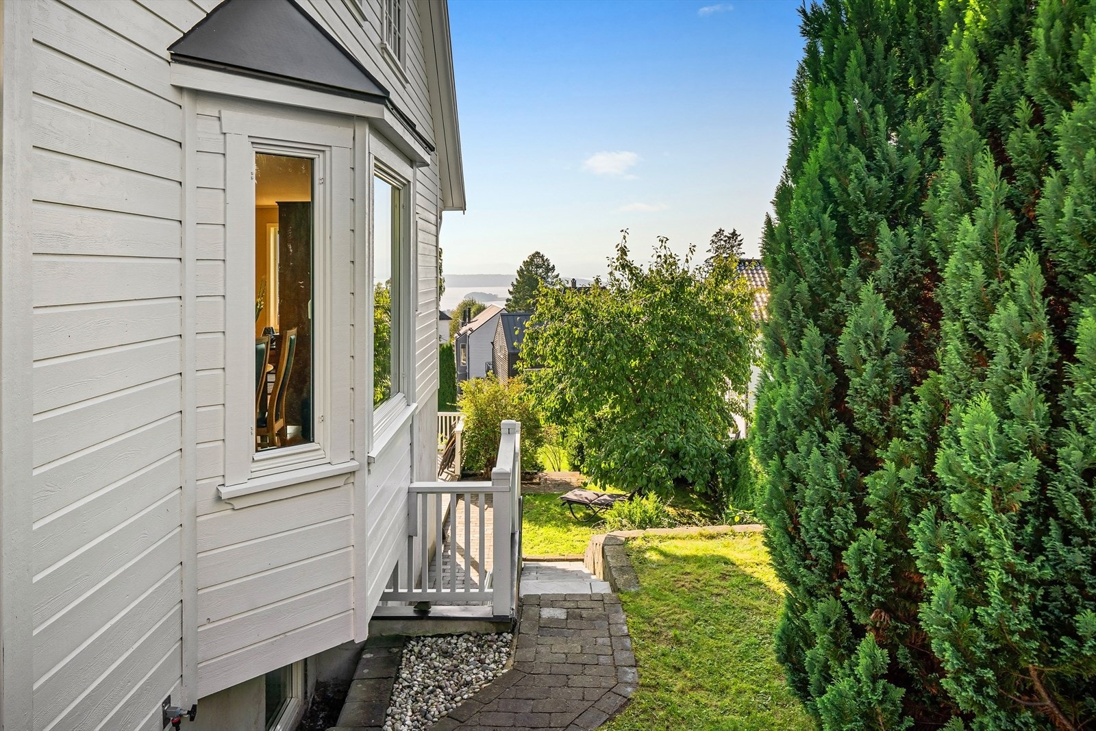 Kjøkkenvindu sett fra utsiden med nedgang til hage og terrasse. Galleribilde