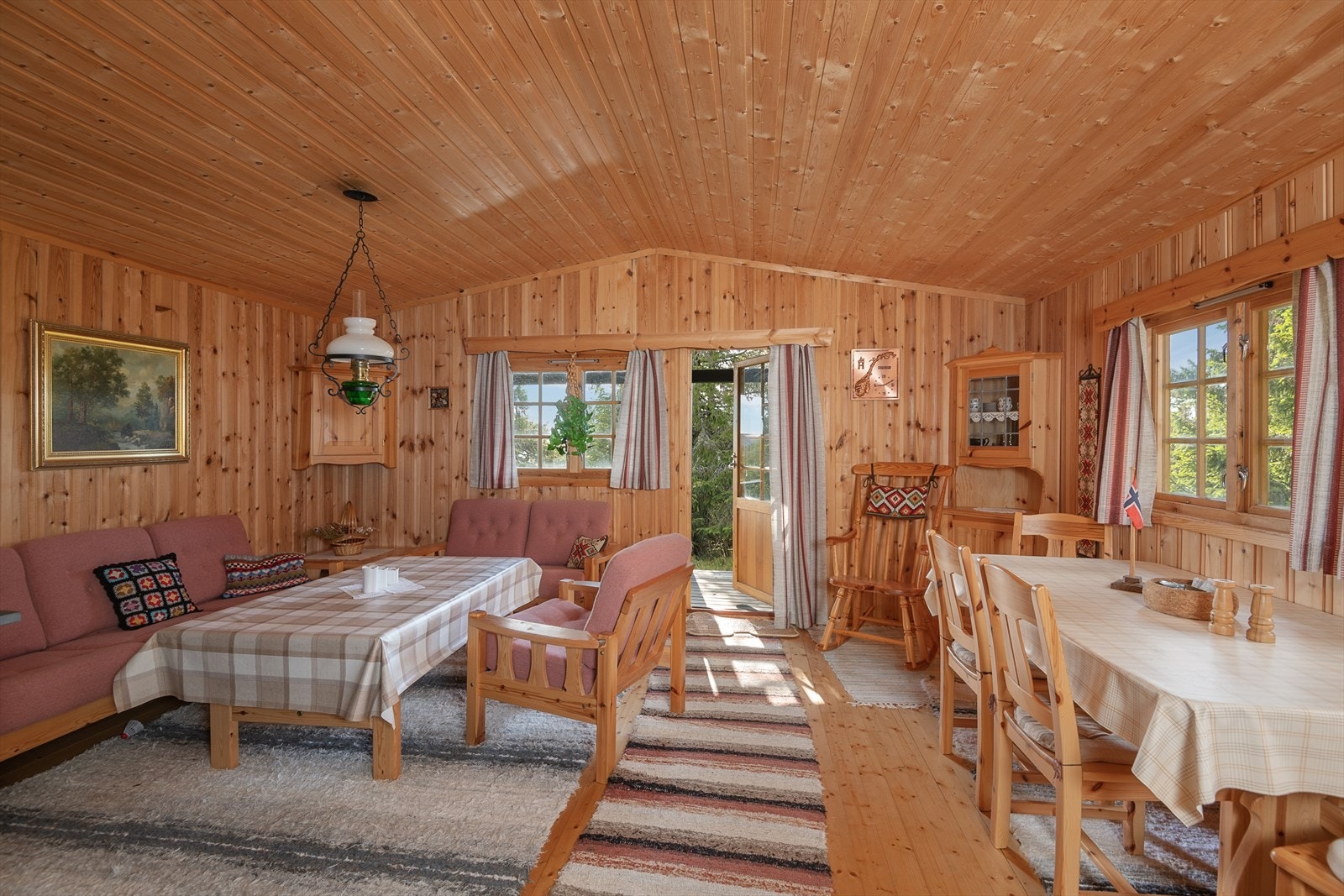 Hyggelig stue/spisestue med tradisjonell standard der det er lakkerte tregulv og panelte vegger og tak. Galleribilde