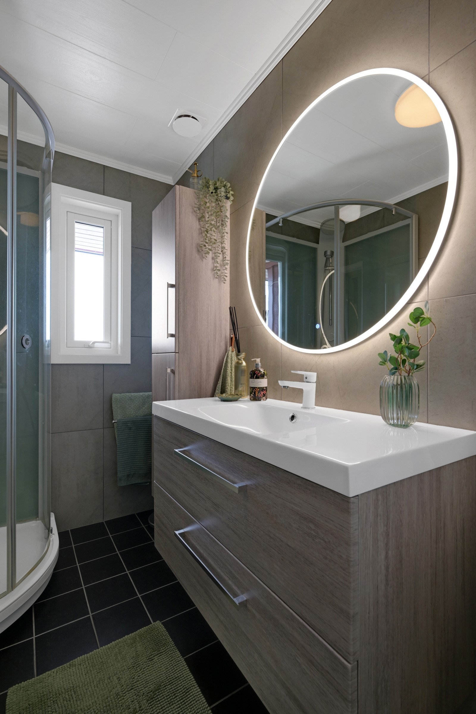 Badet i hovedetasjen er innredet med dusjkabinett, klosett og pen baderomsinnredning med speil. Galleribilde