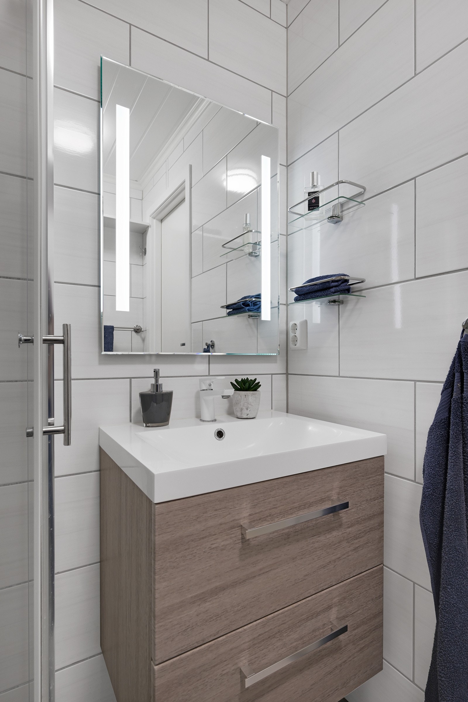 Badet er innredet med praktiske glassdører, vegghengt klosett og pen baderomsinnredning med speil. Galleribilde