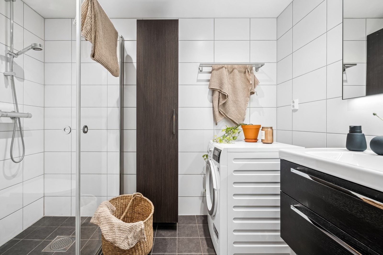 Pent flislagt baderom med opplegg for vaskemaskin og tørketrommel. Godt med oppbevaringsplass i skap og skuffer under servant. Galleribilde