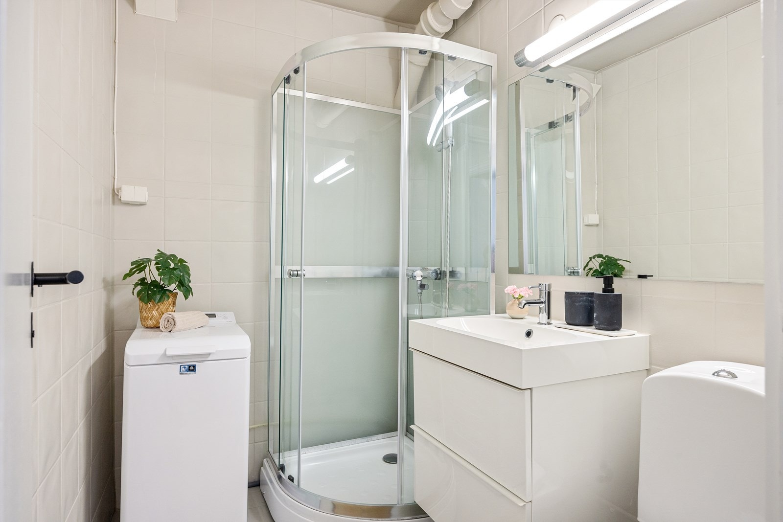 Pent flislagt baderom med gulvvarme. Badet består av servantskap med høyglansfronter og heldekkende servant, speil og lysarmatur på vegg over servanten, samt gulvmontert klosett med utvendig sisterne. Galleribilde
