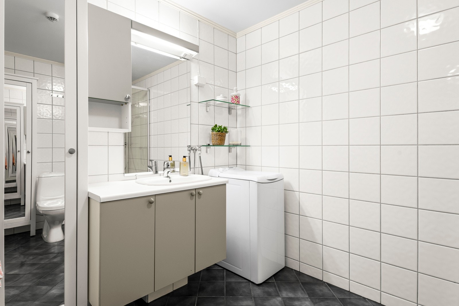 Badet har innredning med glatte fronter på underskap og veggskap, nedfelt servant og speil med belysning. Galleribilde