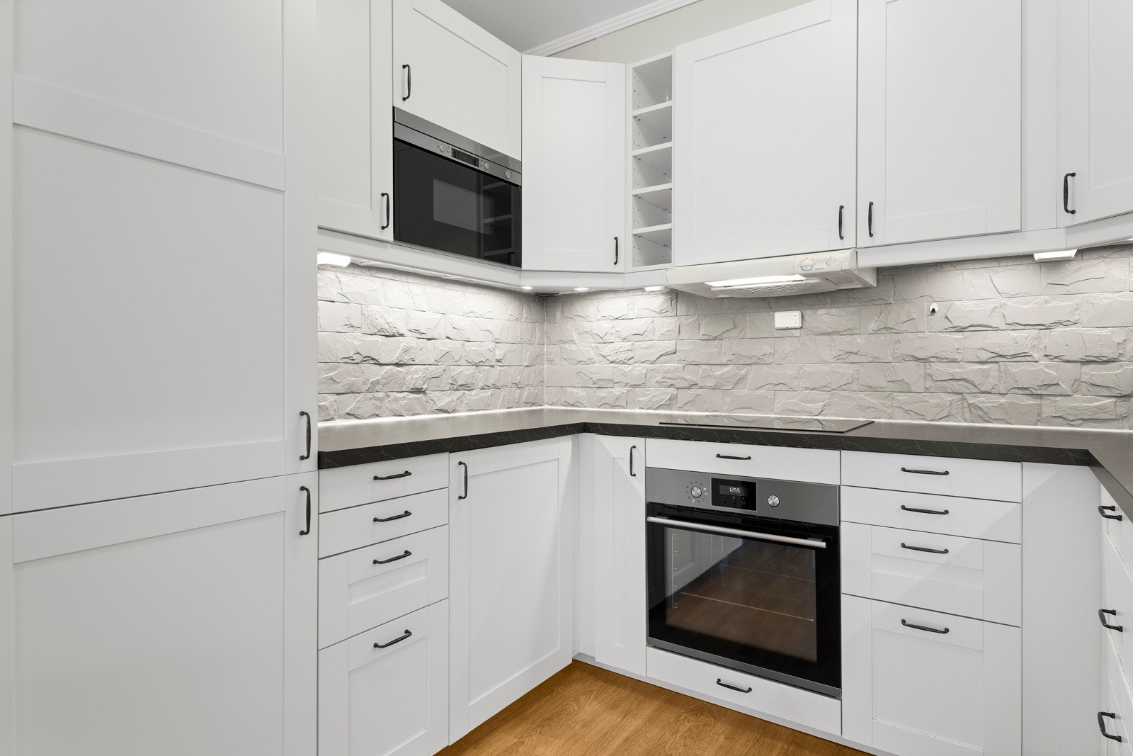 Innredningen har hvite, profilerte fronter, åpne hyller og mørk laminatbenkeplate. Galleribilde