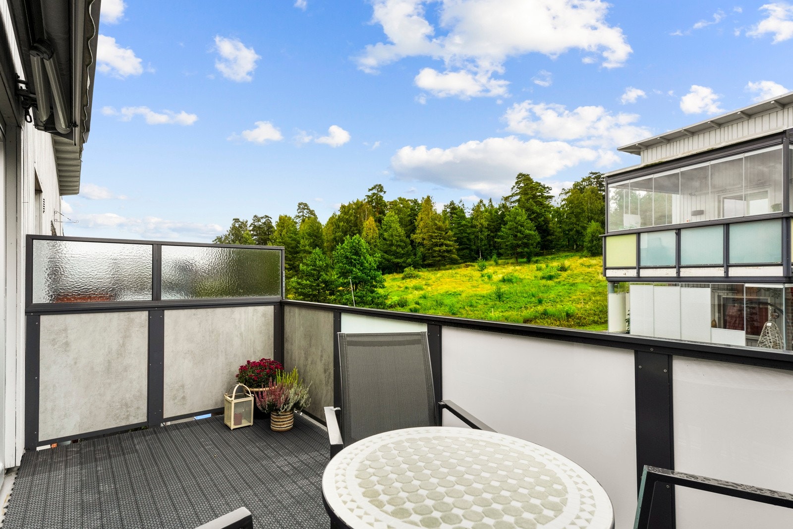 Balkongen har plastheller over betongdekke, tett rekkverk og små levegger på hver side. Galleribilde