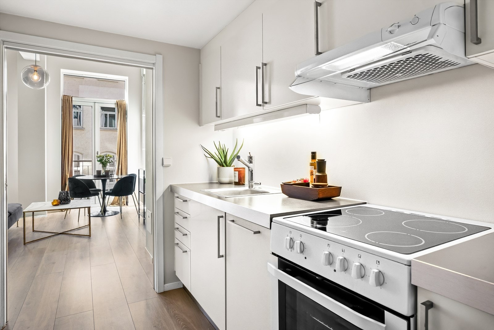 Stilrent og moderne kjøkken i delvis åpen løsning med stuen, adskilt med skyvedør. Kjøleskap i en nisje bak veggen med lysbryteren. Galleribilde