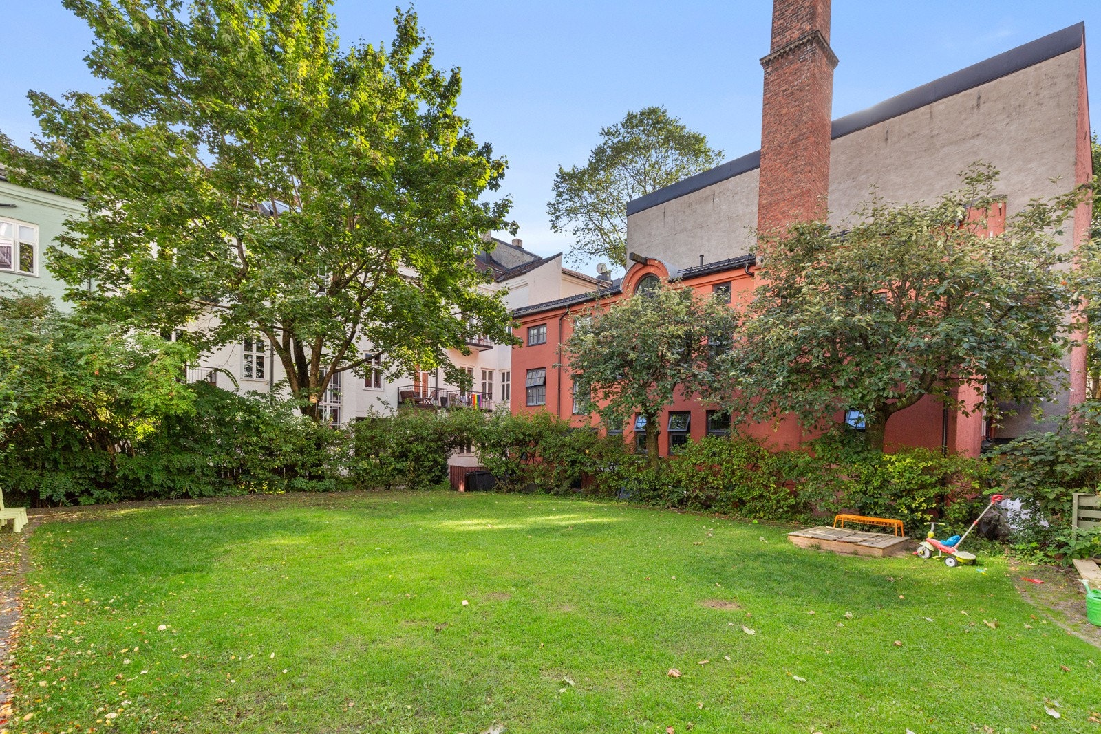 Bakgården er en vakkert opparbeidet grønn oase, med plen og grønn beplanting. Galleribilde