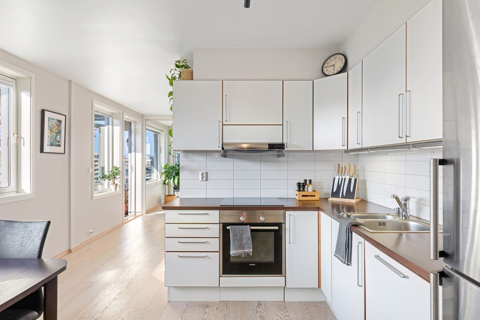 Tidløst og pent kjøkken med hvite glatte fronter og benkeplate av laminat Galleribilde