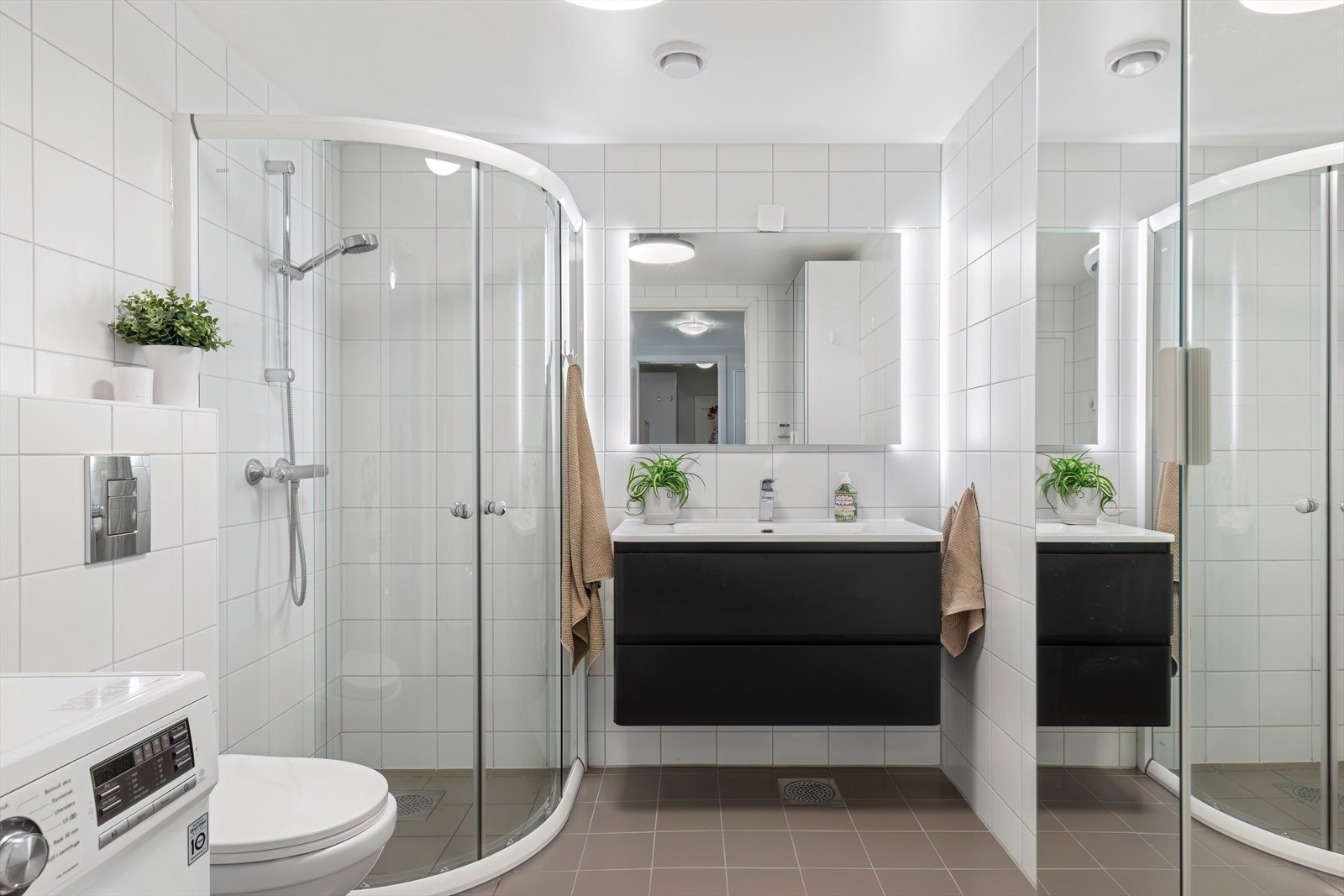 Innbydende helfliset bad med mørke fliser på gulv, samt hvite fliser på vegger Galleribilde