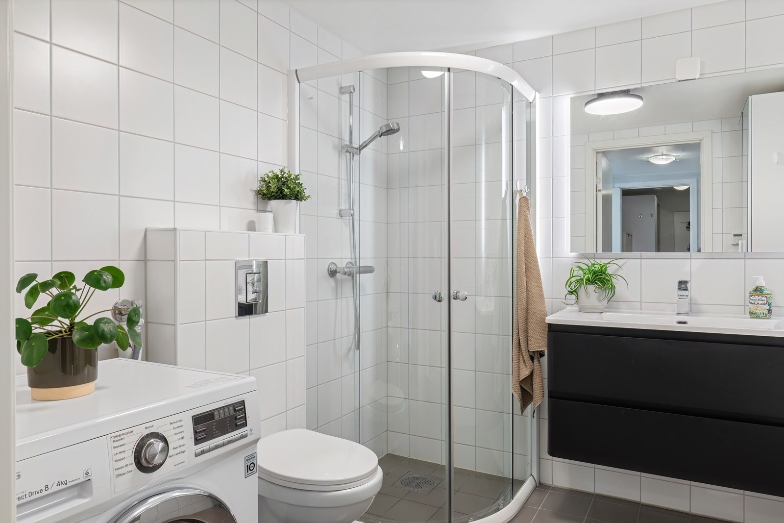 Badet har gulvvarme og er innredet med servant i baderomsmøbel, vegghengt toalett, dusjhjørne og romslig garderobe Galleribilde