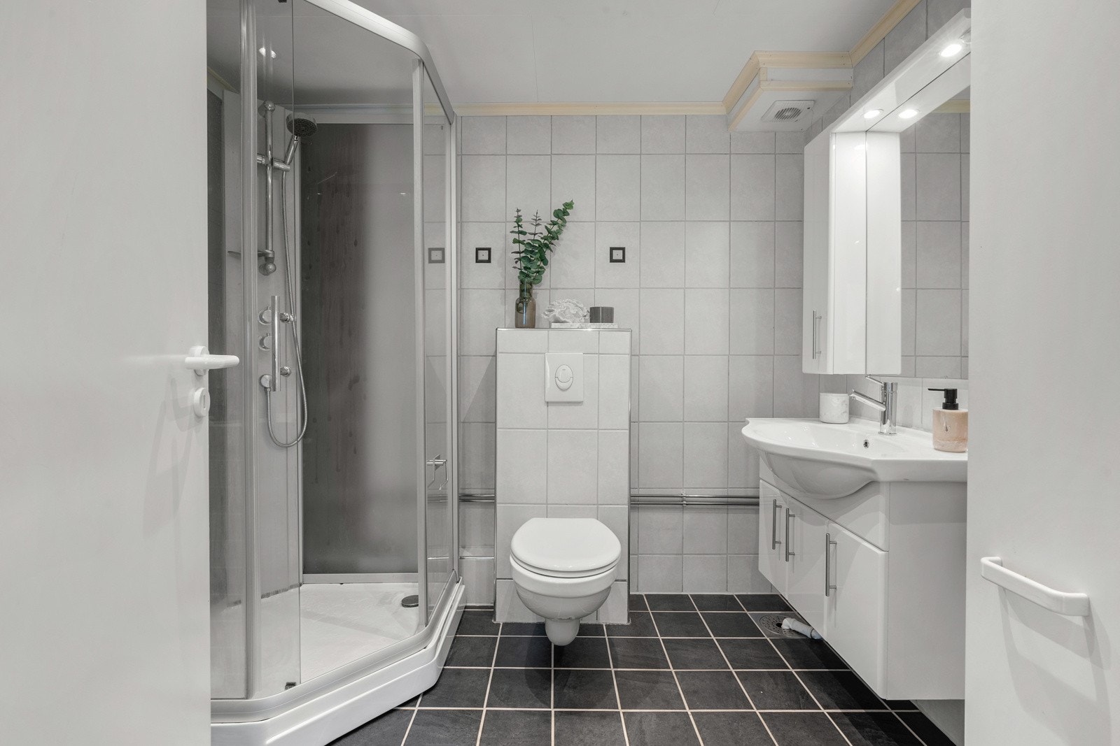 Baderommet er utstyrt med flislagte overflater på både gulv og vegger, noe som gir et tidløst og solid inntrykk. Galleribilde