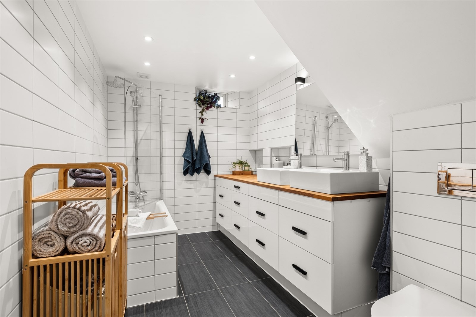 Badet er lekkert og fremstår med hvite veggfliser og mørke gulvfliser. Galleribilde