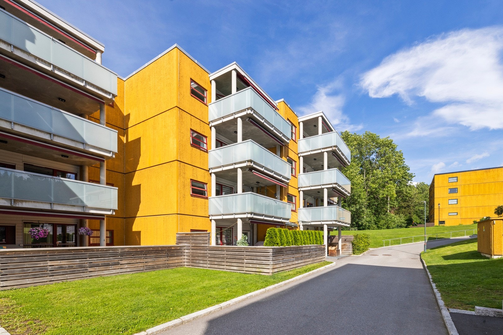 Fellestomten er pent opparbeidet med steinbelagte gangstier, velstelte plenområder, trær, prydbusker og diverse beplantning Galleribilde