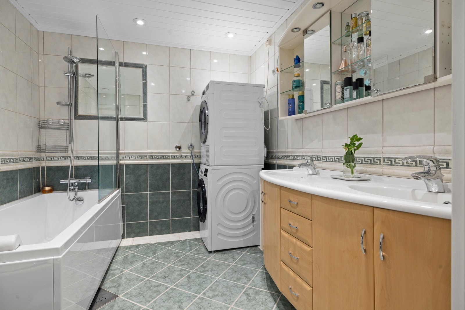 Badet har flislagte overflater, gulvvarme, downlights og opplegg for vaskemaskin Galleribilde