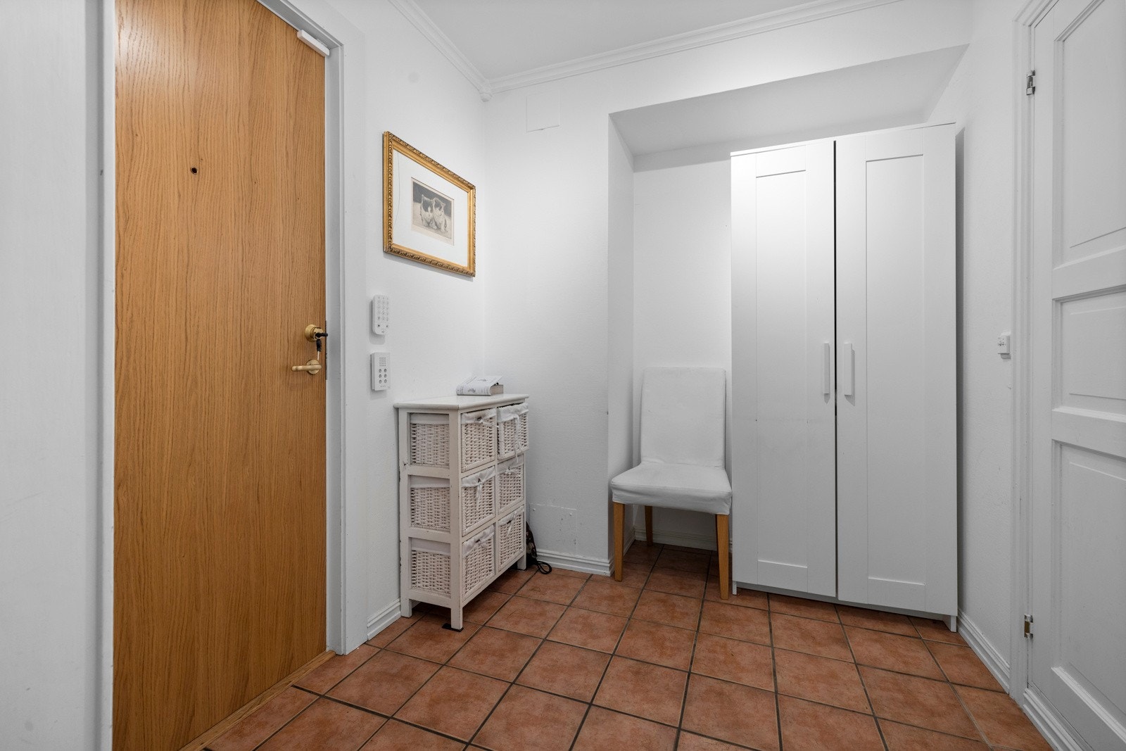 Leiligheten har en innbydende entré med fliser på gulvet og en praktisk nisje med plass til garderobeskap eller lignende Galleribilde