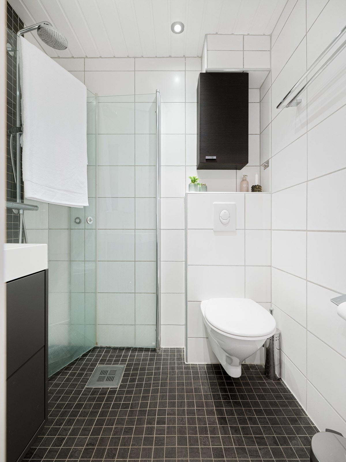 Flislagt bad med varme i gulv. Malt panel i himling med integrert belysning. Innredet med veggmontert wc, servantinnredning og dusjvegger. Galleribilde