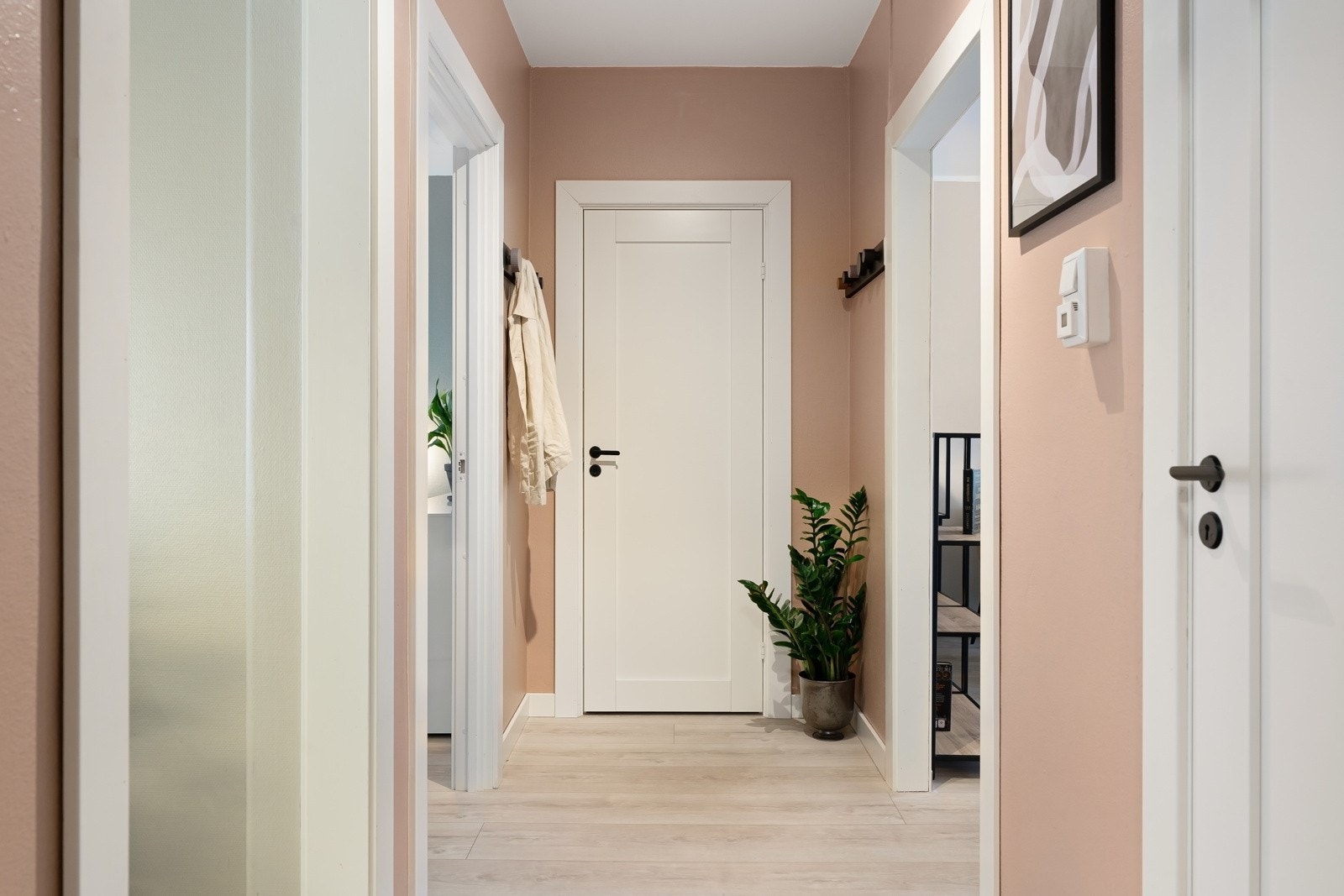 Entreen gir et godt førsteinntrykk med vegger malt i en varm pudderfarge, sorte knagger på veggene og direkte inngang til et omkledningsrom som gjør det enkelt å holde orden. Ved ytterdøren er det montert dørcalling til port og oppgang. Galleribilde