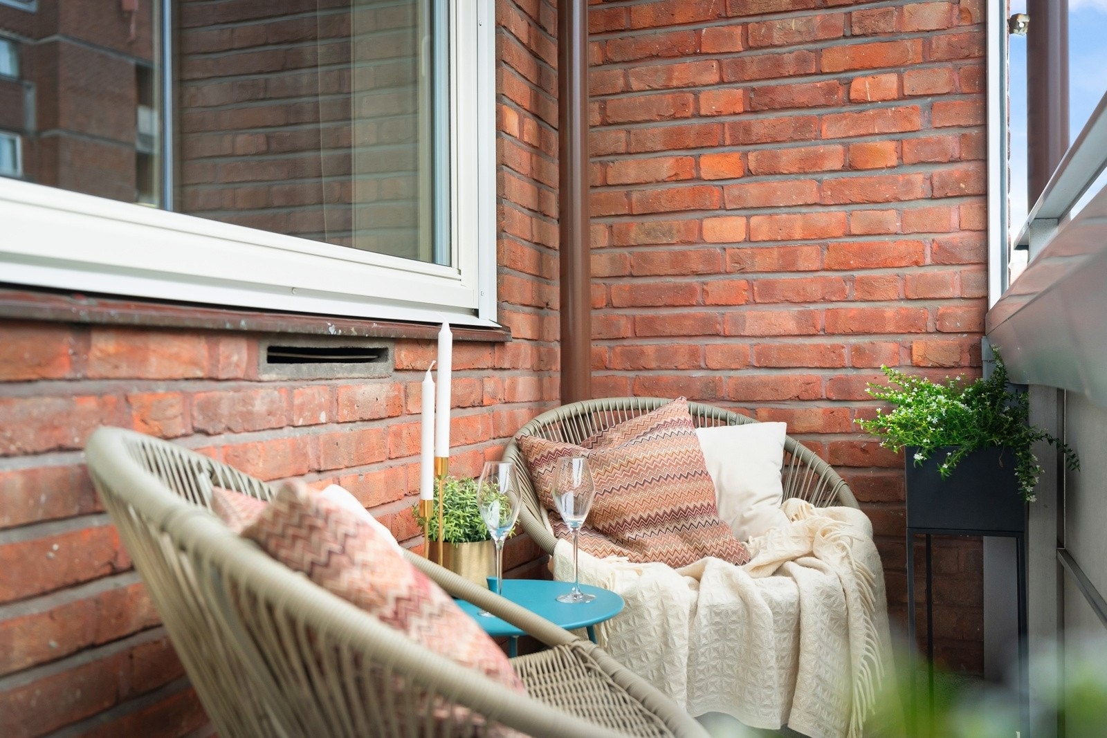 Balkongen har tett, plateslått rekkverk og oppleves som ekstra lun på grunn av fasaden i rød tegl, som danner en rustikk ramme. Balkongdekket er i lettstelt, terrazzobelagt betong, og det er fin plass til et par godstoler. Galleribilde