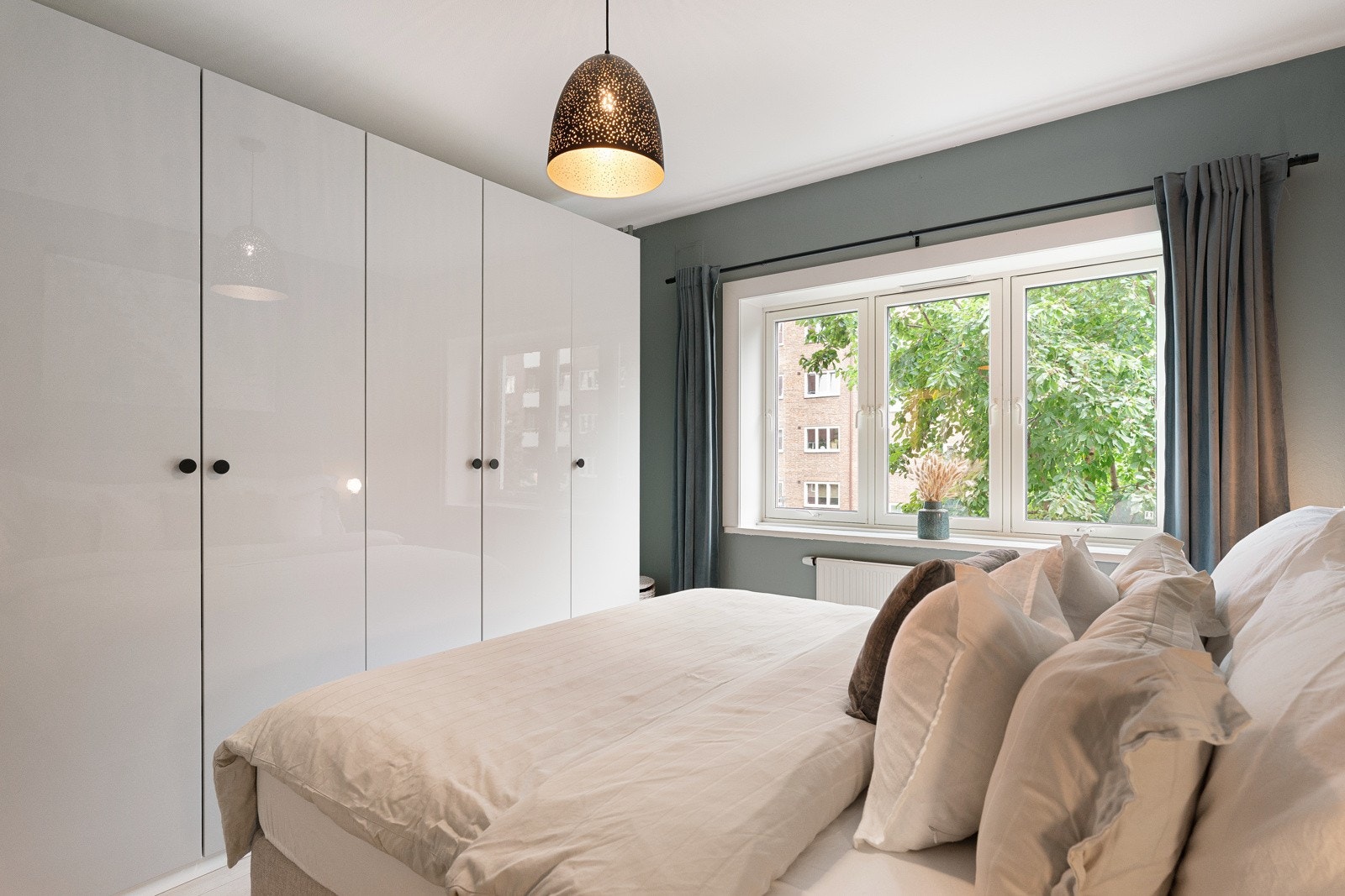 Langs den ene veggen er det montert et femdørs garderobeskap fra 2019 med lyse høyglansfronter, innredning i eikelaminat og innebygd belysning. Galleribilde