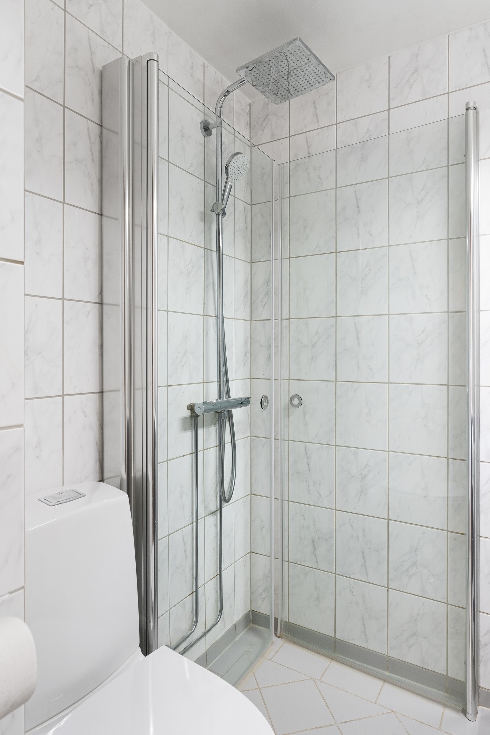 Badet har overflater med lyse fliser, varmekabler i gulvet og opplegg for vaskemaskin i hjørnet av rommet. Galleribilde