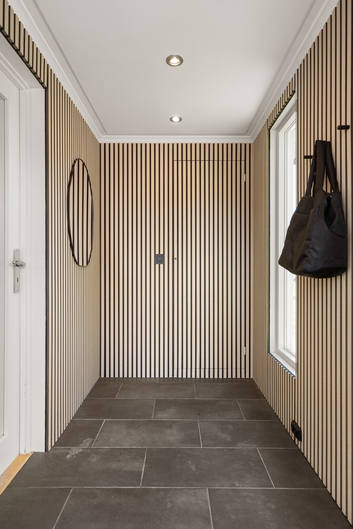 Velkommen inn - flislagt entré med oppheng til yttertøy og skjult garderobe. Galleribilde