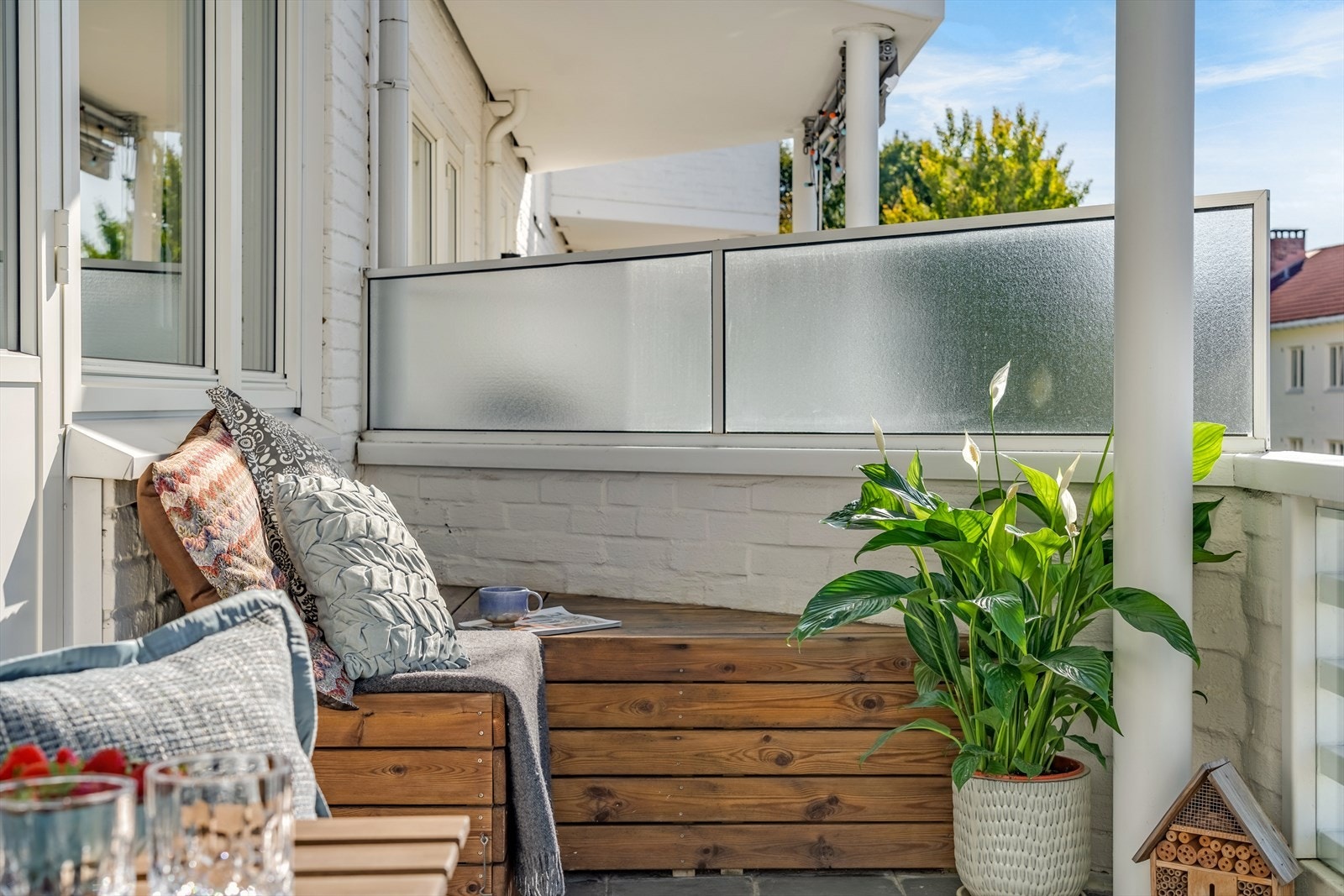 Vestvendt takoverbygd balkong med lagringsbenk. Flislagt dekke, her har er det plass til utemøblement og beplanting. Galleribilde