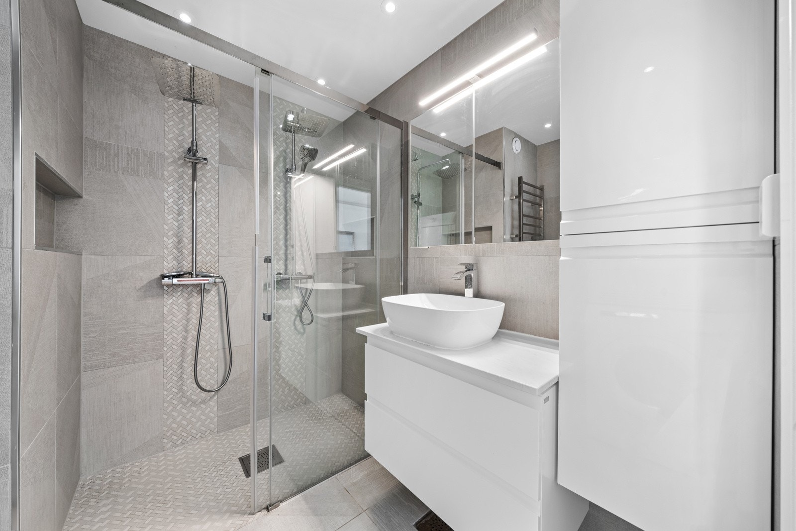 Dette moderne badet kombinerer funksjonalitet og stil, med fliser på både gulv og vegger som skaper en elegant atmosfære. Galleribilde