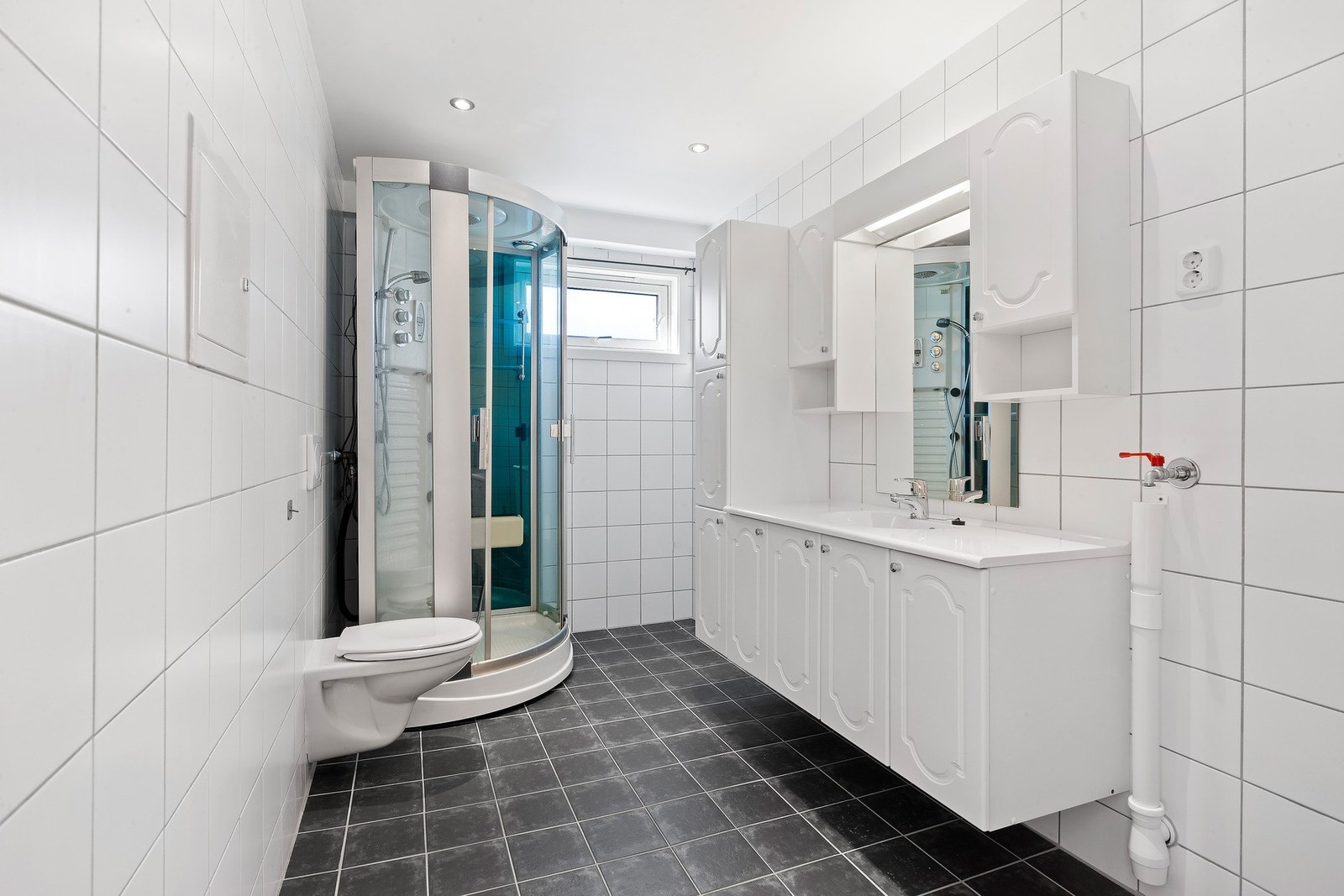 Badet har flis på vegg og flislagt gulv med elektriske varmekabler. Det er gode muligheter for diverse oppbevaring i innredningsskap. Galleribilde
