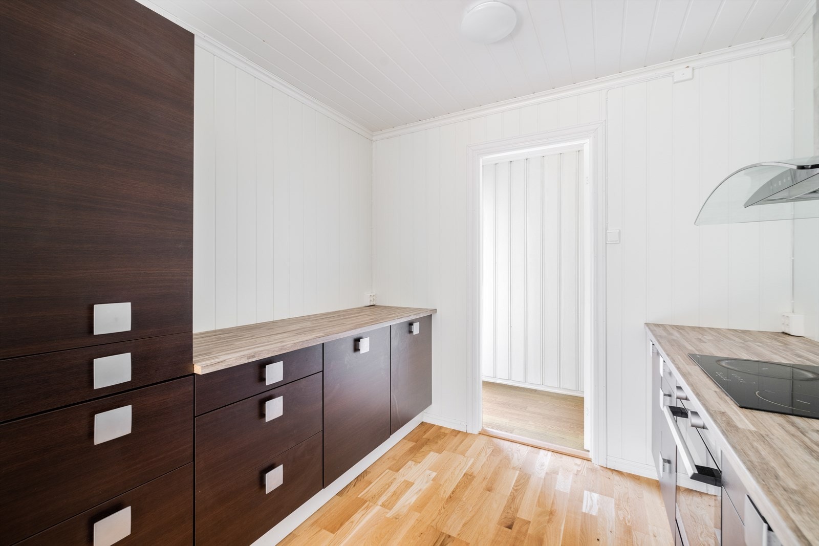 Kjøkkenet har mørk innredning på begge sider av rommet, med glatte fronter og benkeplate av laminat. Galleribilde