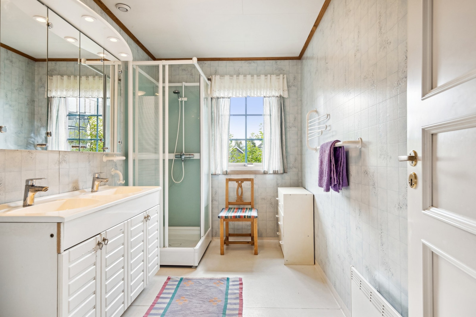 Badet er innredet med heldekkende dobbel servant med underskap, speilskap, toalett og dusjkabinett Galleribilde