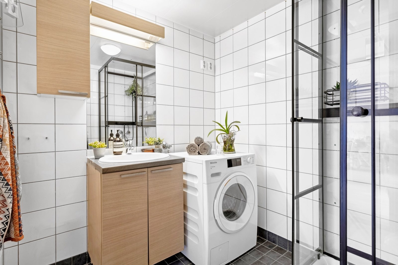 Badet består av vegghengt wc, servant med underskap, innfliset speil med overlys, veggskap, dusjkabinett (fra 2021) og opplegg for vaskemaskin Galleribilde