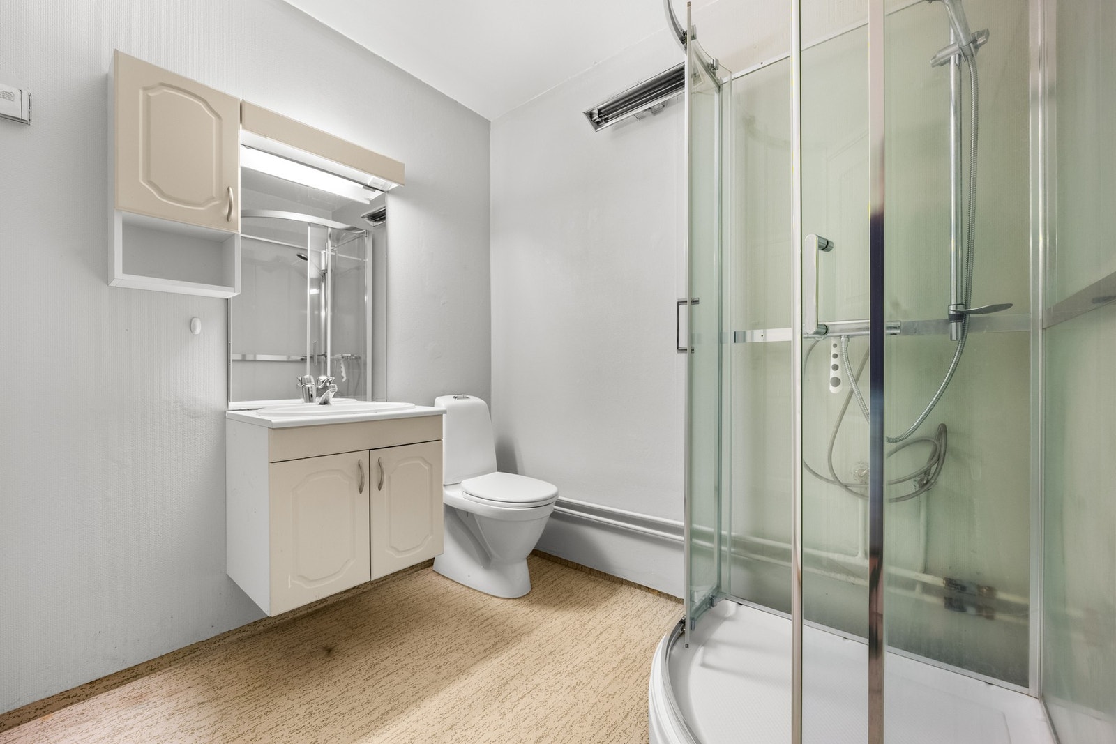 Badet har belegg på gulv og malt tapet på vegger. Det er utstyrt med servant nedfelt i innredning speil og belysning, samt WC og dusjkabinett Galleribilde