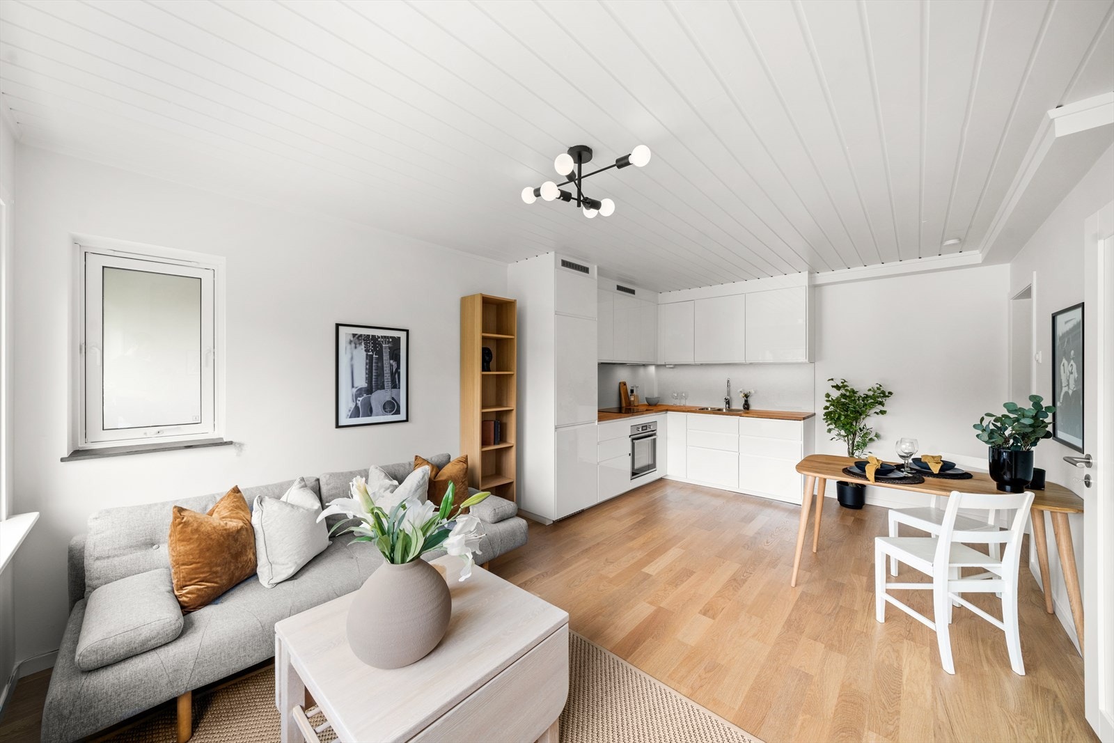 Den plasseffektive, åpne planløsningen kombinerer kjøkken og stue. Kjøkkenet har en stilren innredning med glatte fronter, integrerte hvitevarer, og en tiltalende utførelse. Galleribilde