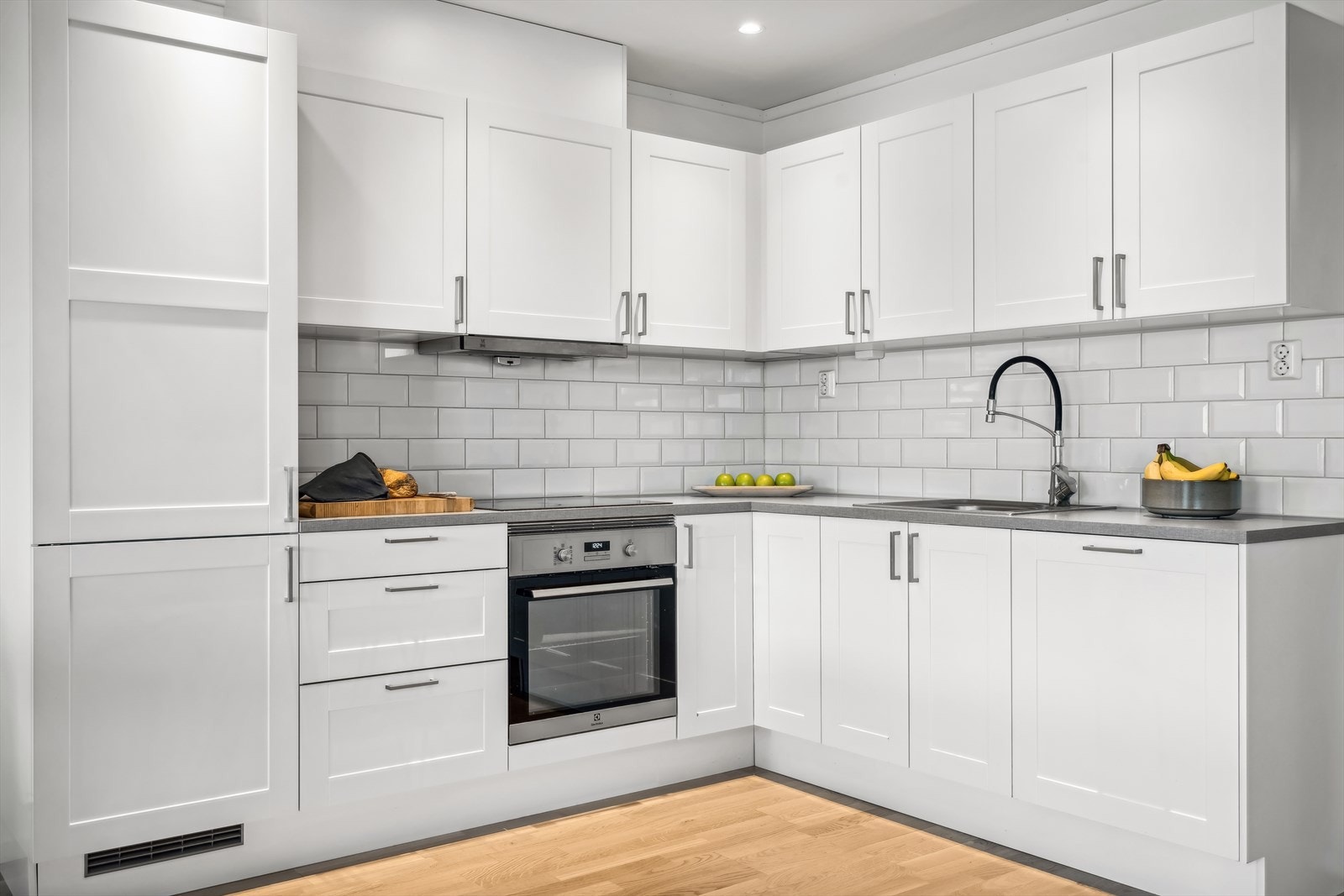 kjøkkeninnredning bestående av profilerte fronter. Fliser på vegg over benkeskap, laminat, benkeplate med nedfelt kum i rustfritt stål og ventilator. Galleribilde