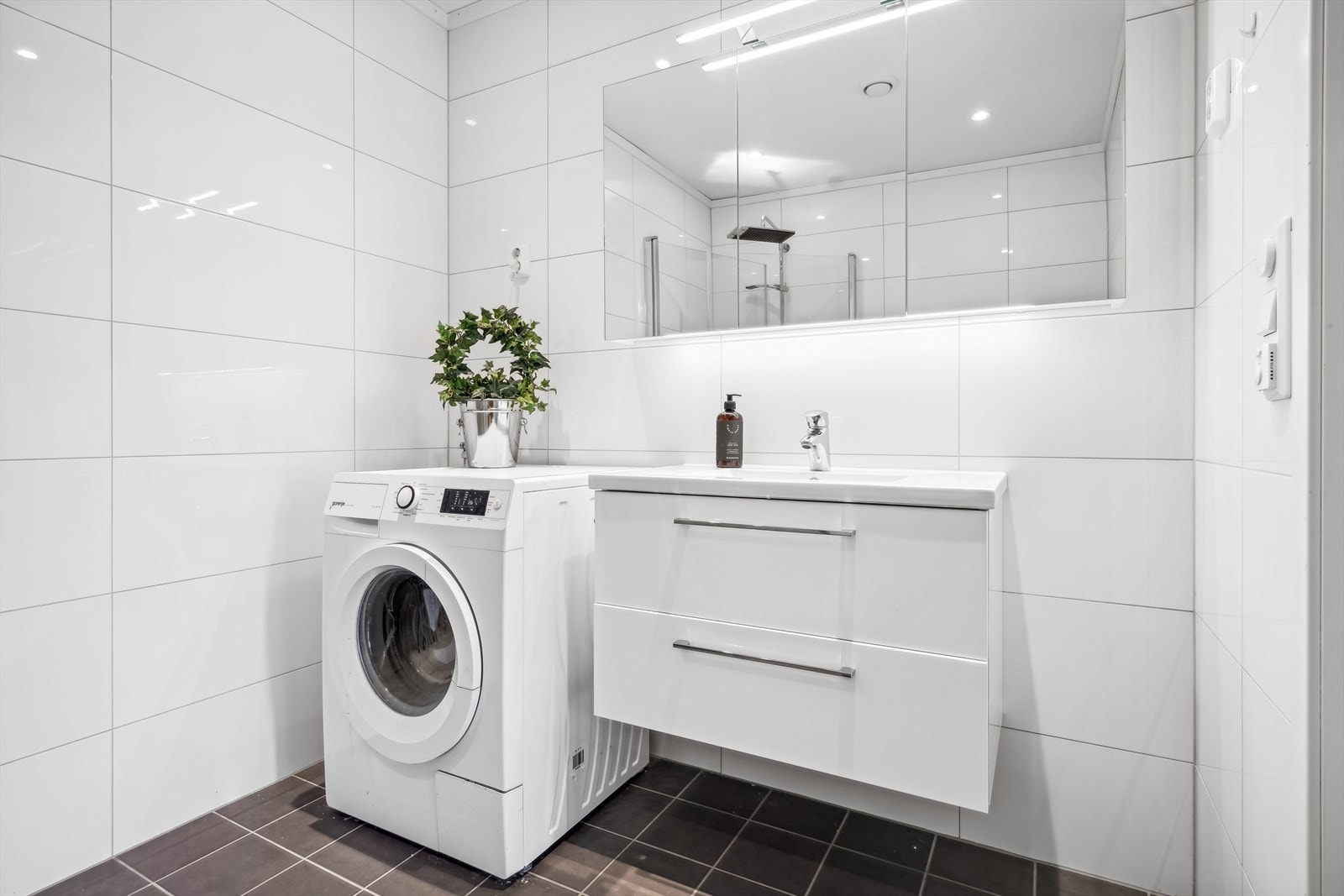 Baderommet har en baderomsinnredning bestående av benkeskap med glatte fronter. Veggskap med speilfronter og belysning over servant. Galleribilde