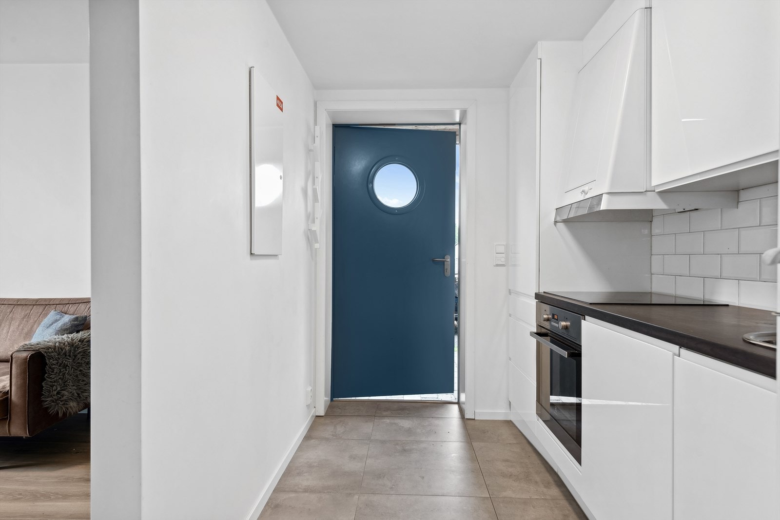 Lys innredning, mørkere benkeplate og hvitevarer som platetopp, stekeovn, oppvaskmaskin og kjøleskap. Galleribilde