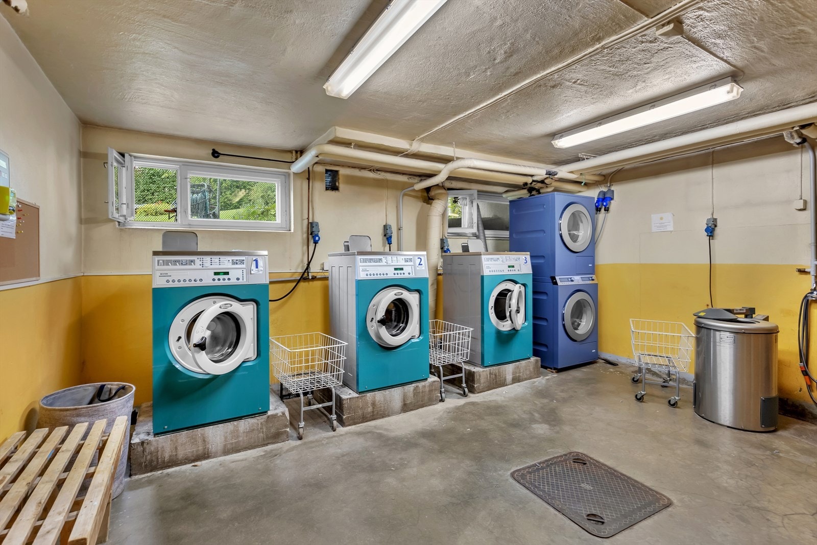 Fin og effektiv vaskekjeller hvor man har 3 industri vaskemaskiner, tørketrommel og tørkeskap. Galleribilde