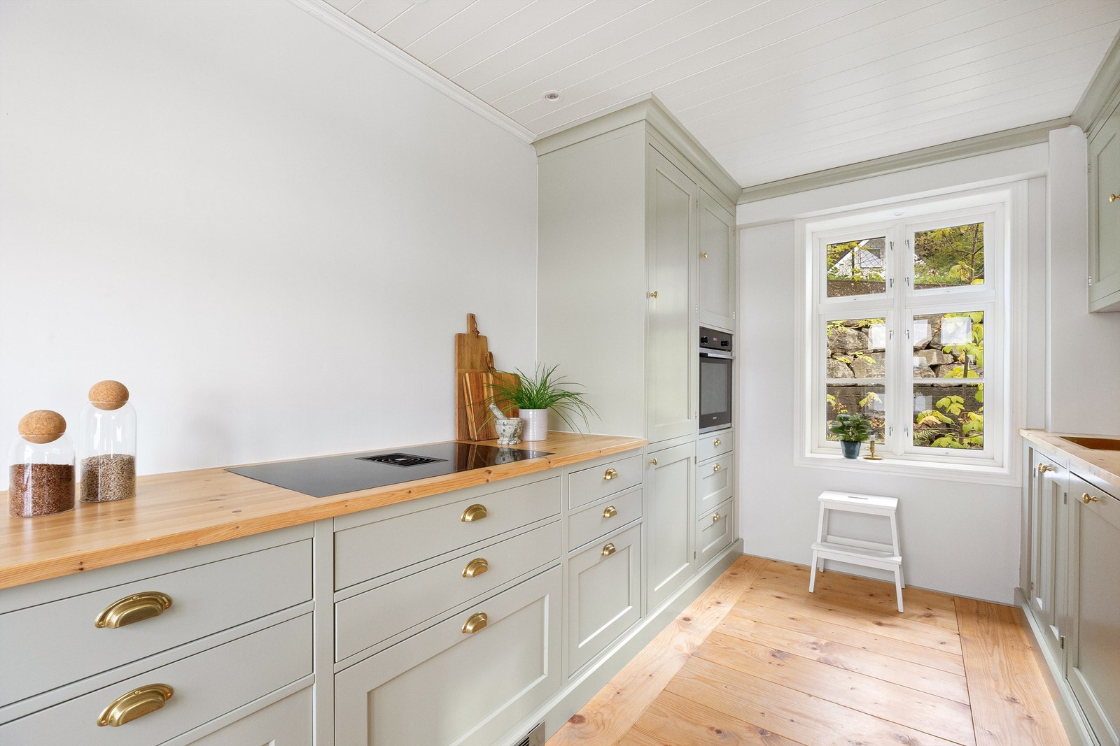 Lekkert, heltre kjøkken med integrerte hvitevarer. I benkeplaten er det nedfelt keramisk steketopp med integrert ventilator. Galleribilde