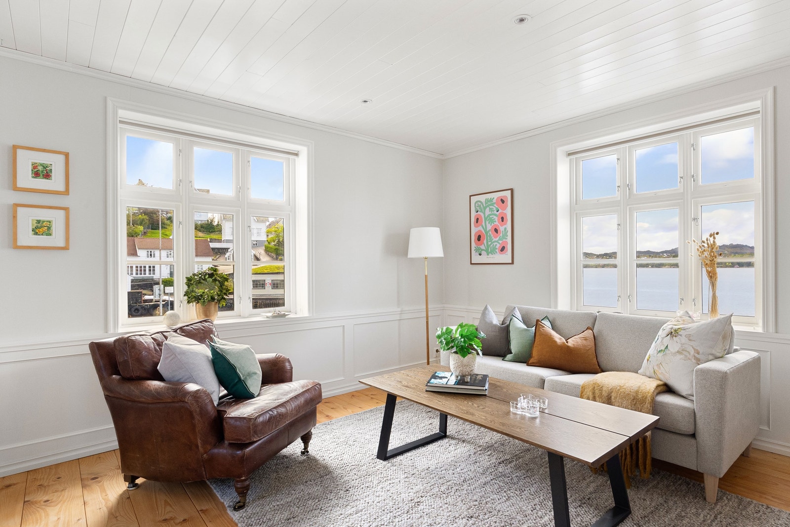 Stue med hvitmalte overflater og eksklusivt heltre gulv med brede, solide plank. Her er det bare å nyte detaljene i arbeidet som er utført. Galleribilde