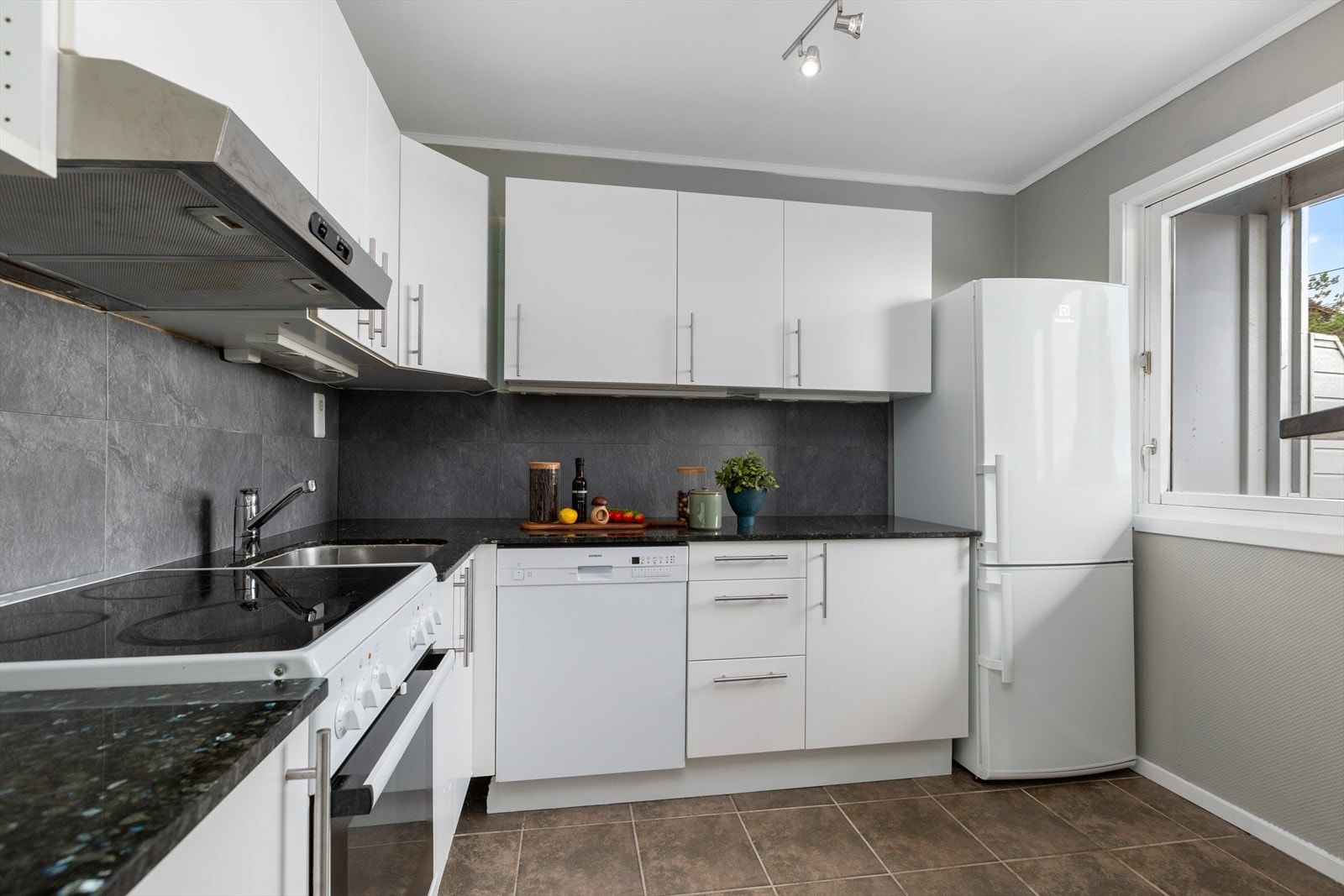 Kjøkkenet har hvite slette fronter. Her er det komfyr, oppvaskmaskin og plass til kjøleskap. Galleribilde