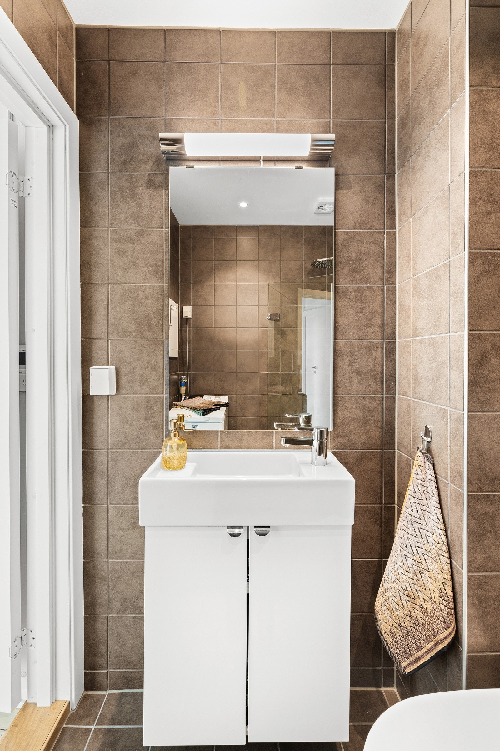 Badet er innredet med nytt servantskap fra Grohe, veggmontert wc med spyling, dusjhjørne med regnfallsarmatur og opplegg for vaskemaskin. Galleribilde