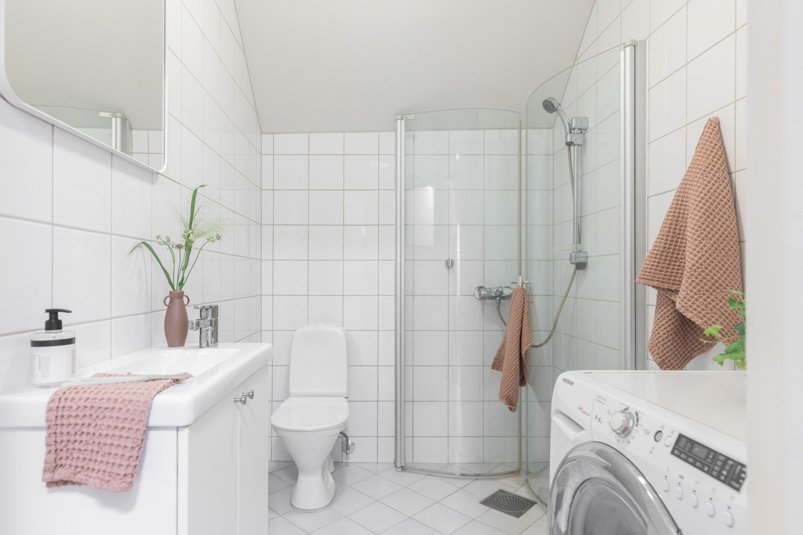 Helfliset bad som er innredet med baderomsmøbel og servant, toalett og dusj. Galleribilde