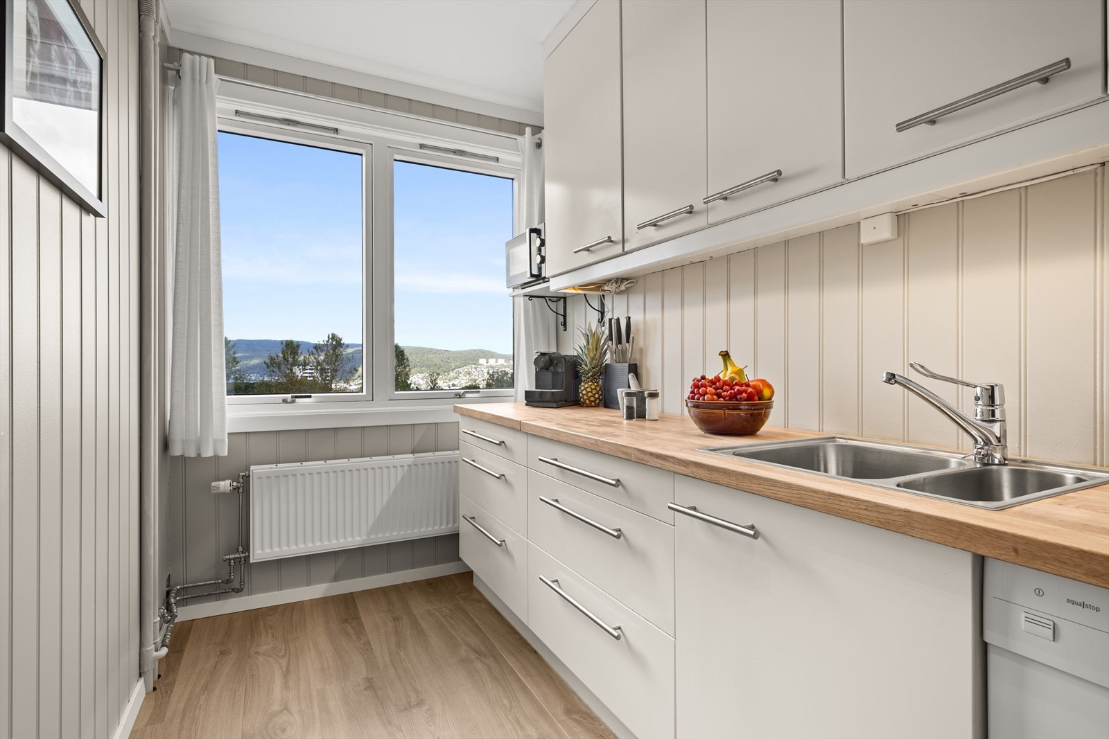 Lettstelt kjøkkeninnredning med glatte fronter, samt nisje for hvitevarer Galleribilde