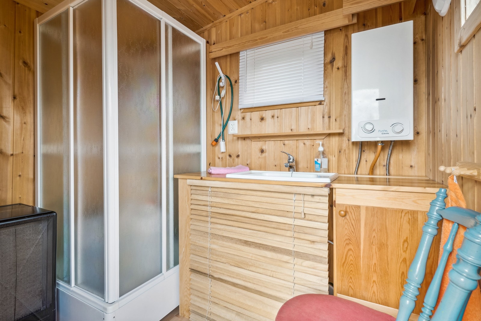 Dusjboden har stående panel på veggene og laminat på gulvet. Rommet er innredet med dusjkabinett og nedfelt servant montert i benkeplate med en skapseksjon og persienner som dekker under benken. Rommet har naturlig avtrekk. Galleribilde