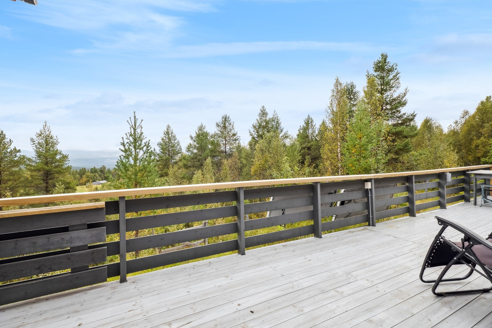 Romslig terrasse som strekker seg rundt store deler av hytta Galleribilde