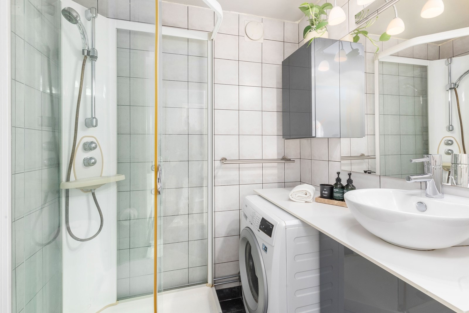 Flislagt bad med varmekabler i gulv. Badet har dusjkabinett, servant med underskap og overspeil. Galleribilde