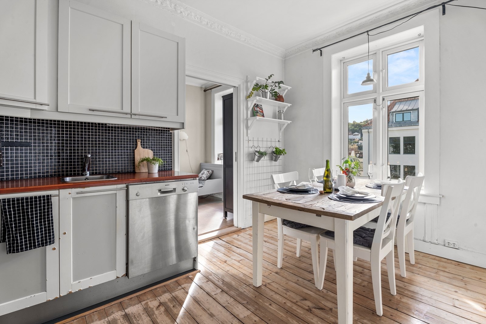 Kjøkkeninnredning med slette fronter og laminert benkeplate med nedfelt stålkum. Nisje til oppvaskmaskin, komfyr og kjøleskap. Galleribilde