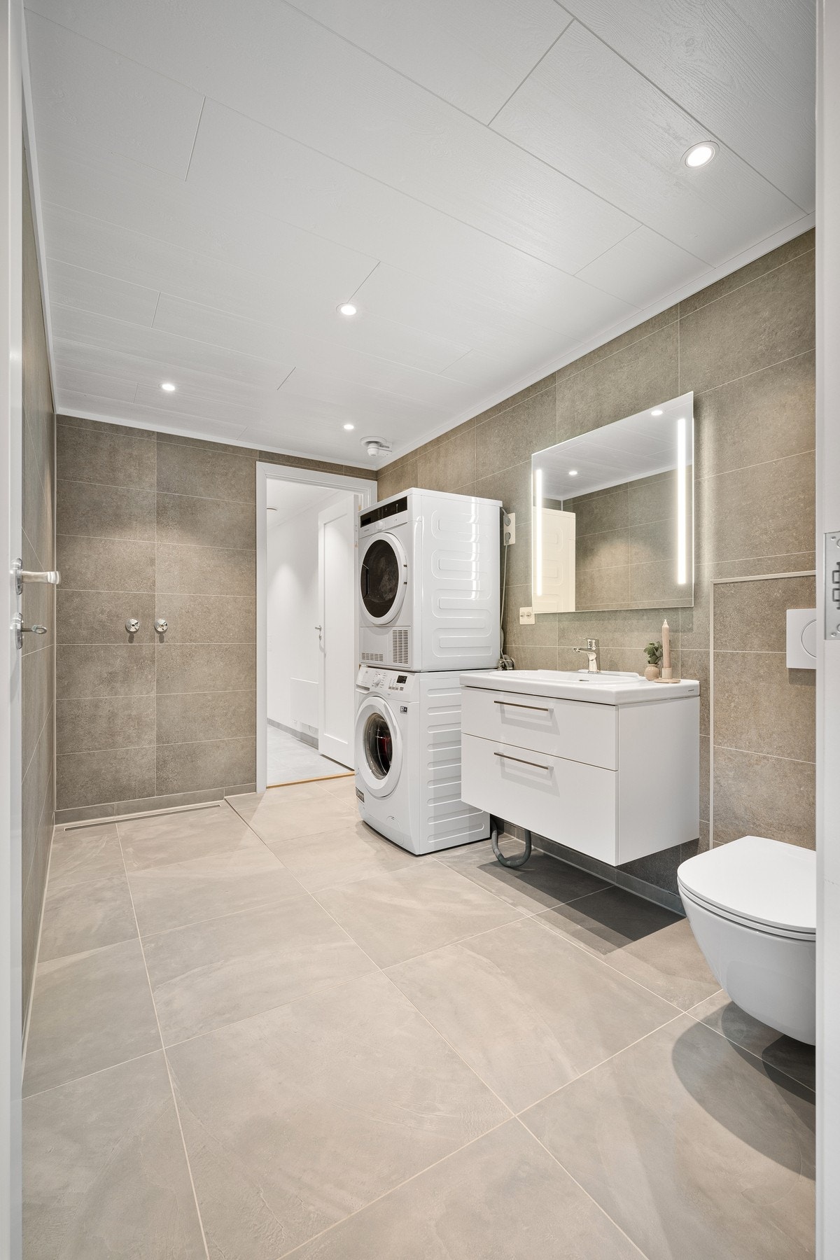 Bad/vaskerom har flislagt gulv med varme, opplegg for vaskemaskin og tørketrommel og klargjort for et dusjhjørne Galleribilde